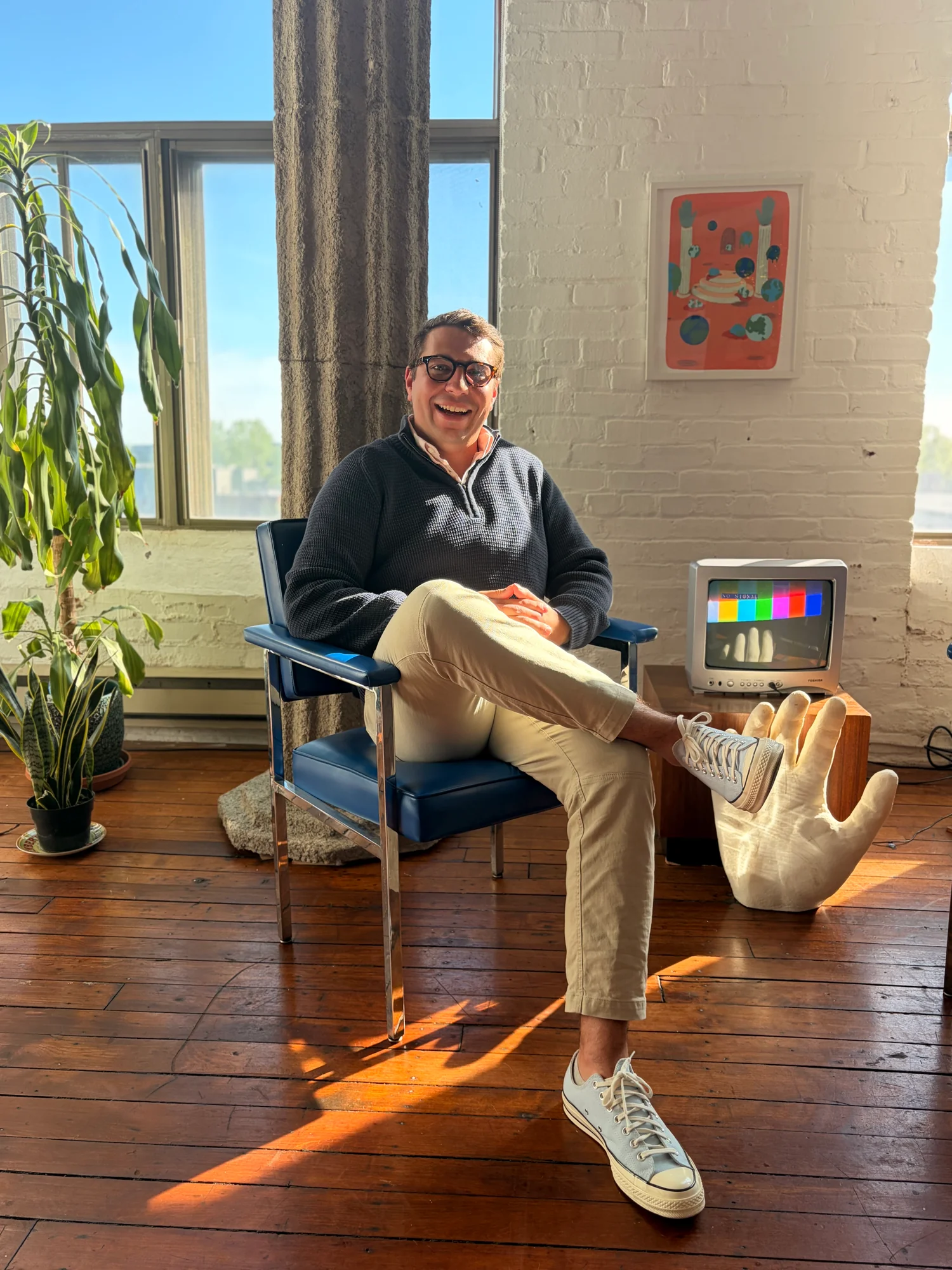 Jakeob smiling in a sunlit room, seated beside a vintage television